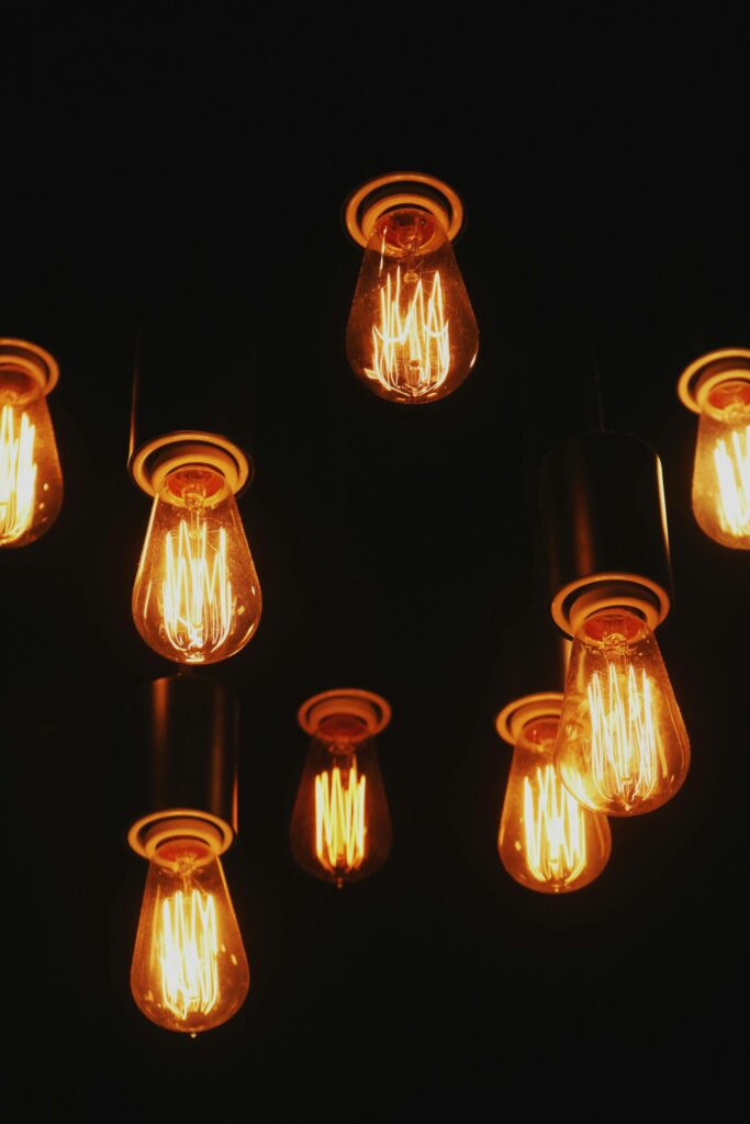 Multiple vintage Edison lightbulbs glowing warmly against a dark backdrop.