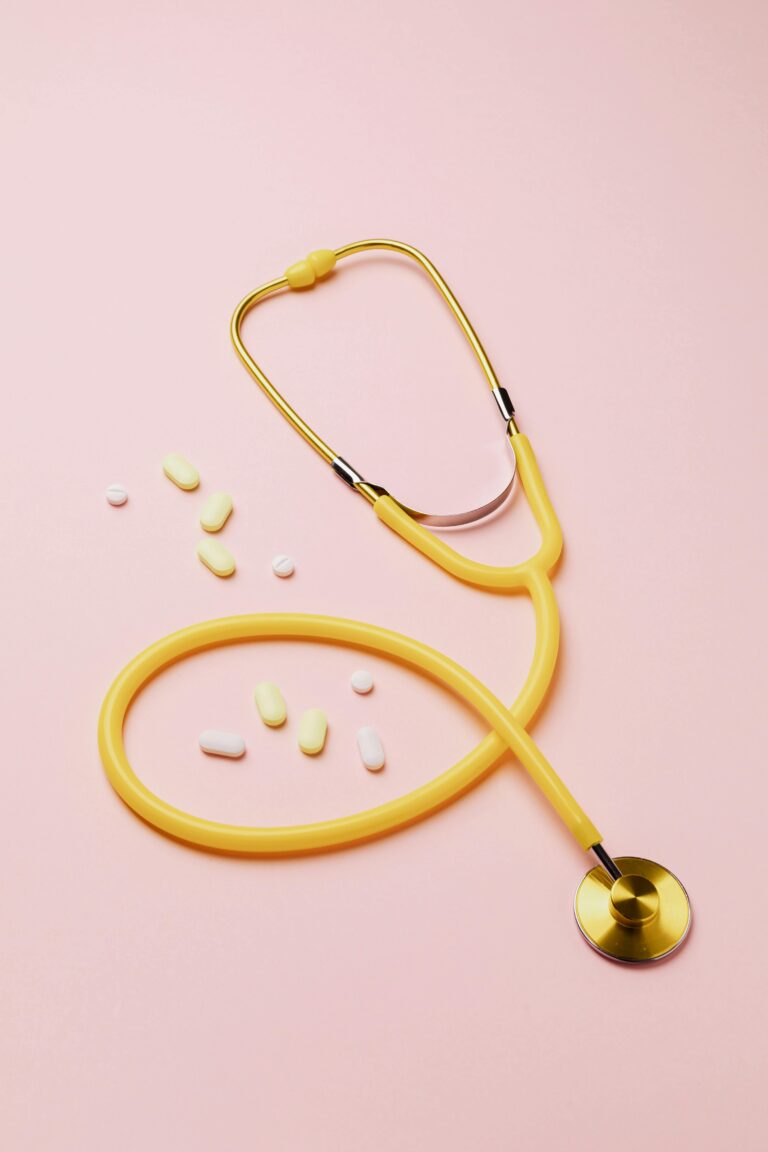 Home A yellow stethoscope and assorted pills on a pink background symbolize healthcare and treatment.
