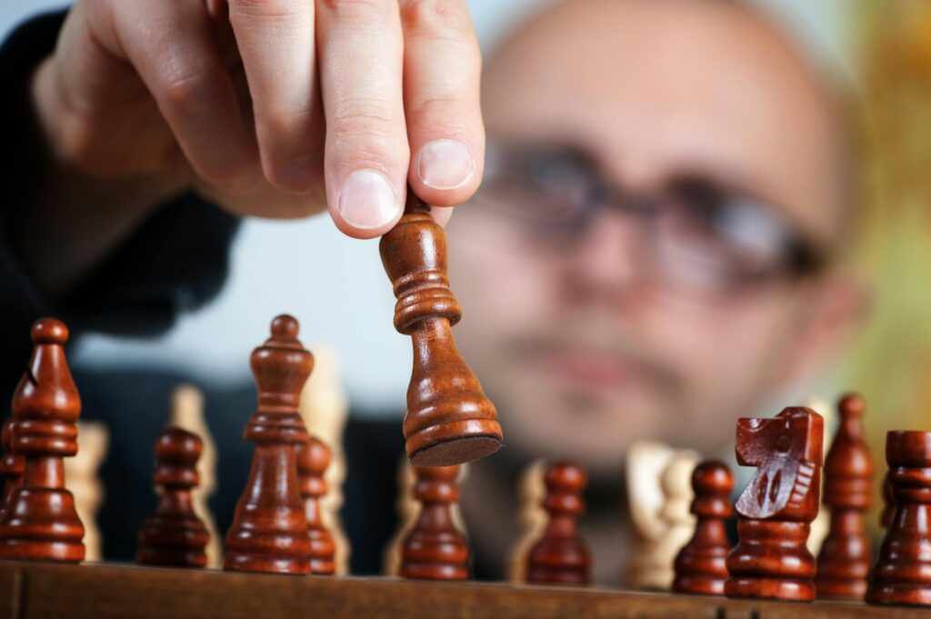 Close-up of a chess player making a strategic move with a focus on the chess piece and the player's intent.
